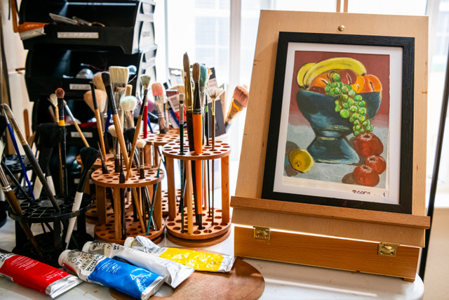 John Boone in his Bay Area studio with paintbrushes and artwork