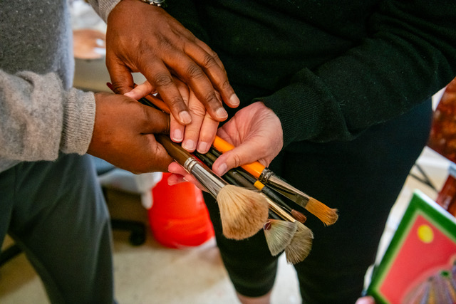Artists holding paintbrushes together