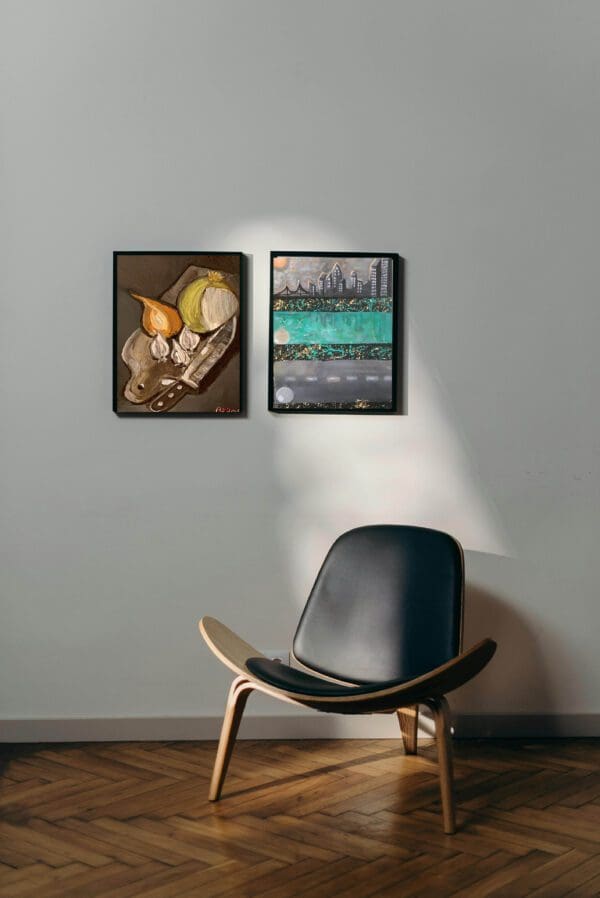 A chair in front of two paintings on the wall.