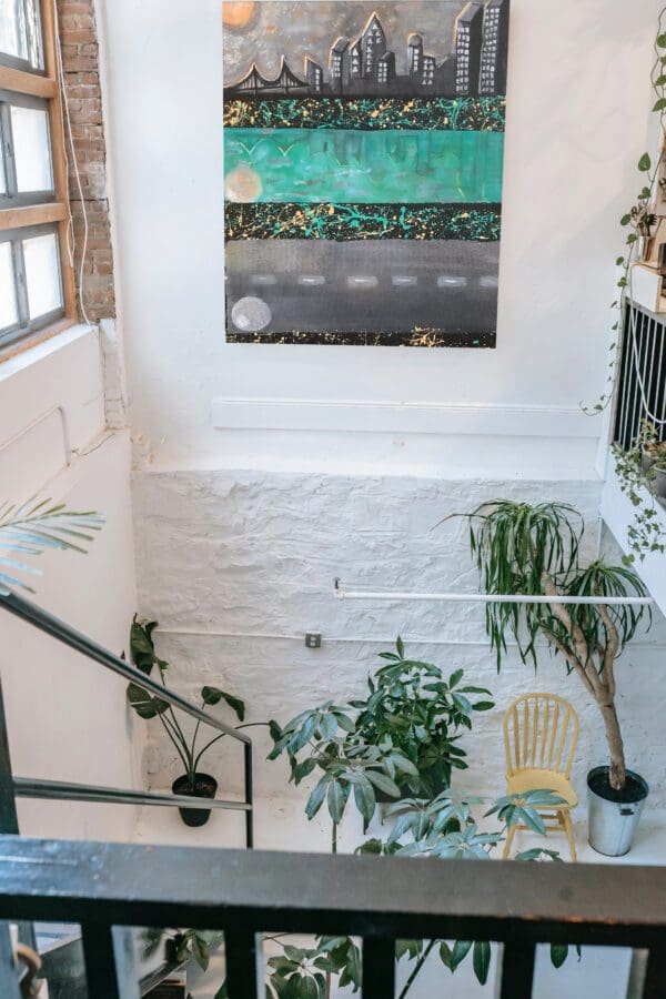 Cityscape painting above plants and stairs.